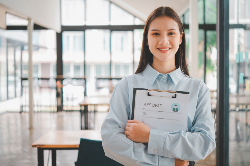 Job seeker holding resume on clipboard inside modern office space.