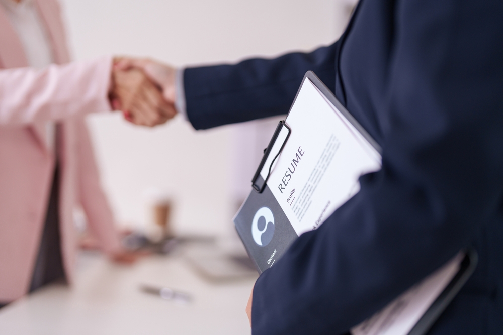 Resume consultant holding a resume while shaking hands with a client.