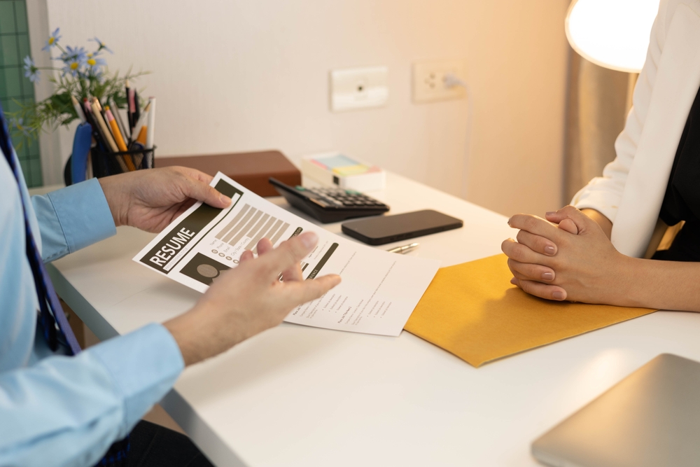 Career advisor reviewing a resume with a job applicant at a desk.