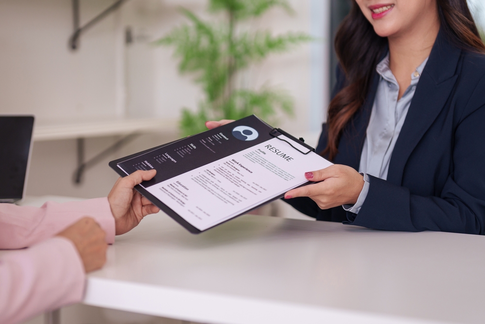 Professional resume consultant handing a printed resume to a client across a desk.