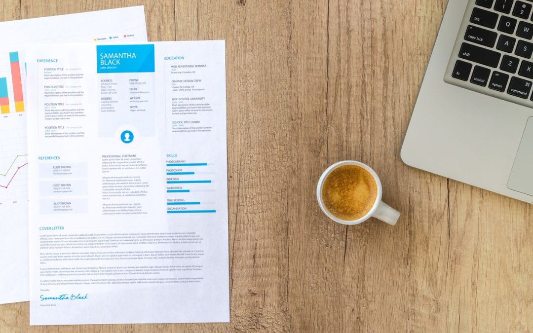 Printed resume beside a laptop and a cup of coffee on a desk